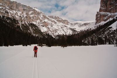 Rear view of people skiing on snowcapped mountain against sky