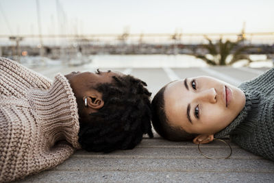 Young woman staring while relaxing with female friend on bench