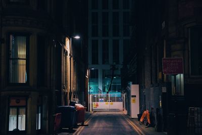 Illuminated street amidst buildings in city at night