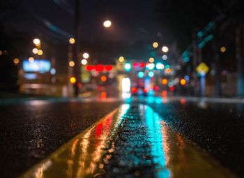 Surface level of wet illuminated street at night