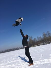 Full length of man jumping on snow covered landscape