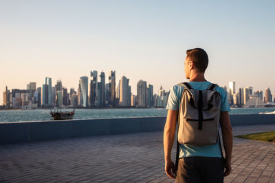 Rear view of man standing against river in city