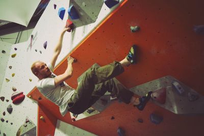 Low angle view of athlete climbing rock wall in gym