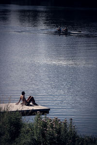 Shirtless man relaxing on jetty by sea