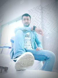Young man sitting on window