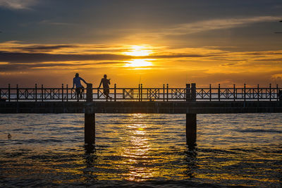 Silhouette people on pier against sky during sunset