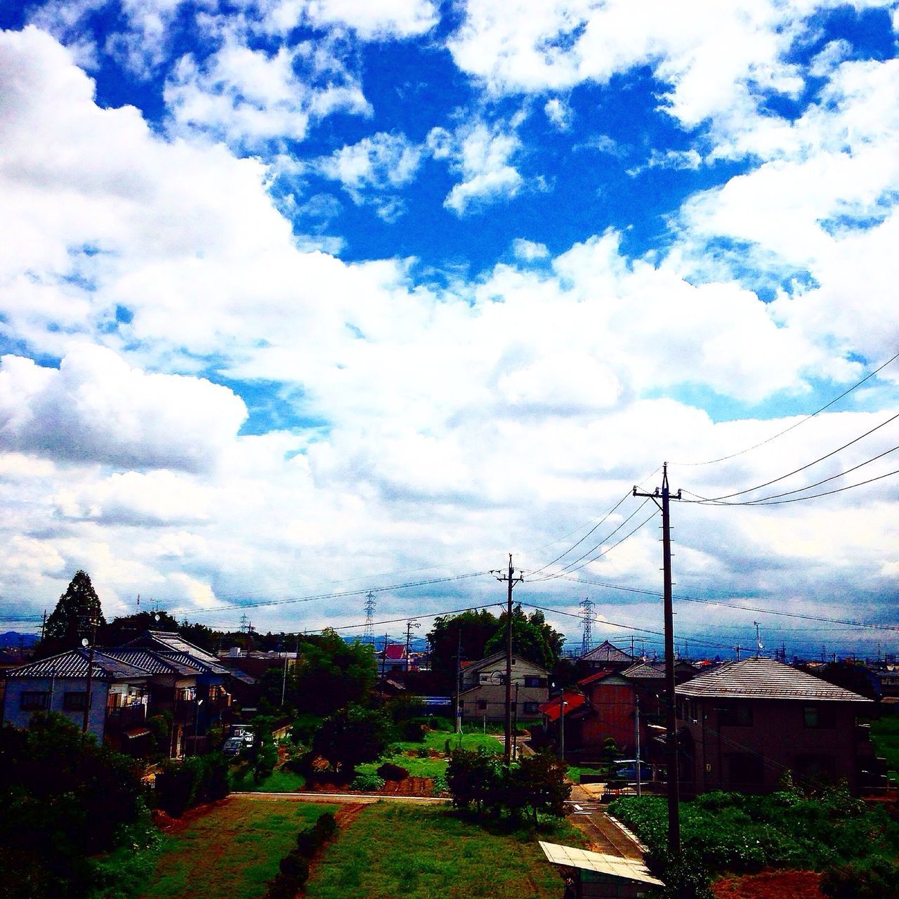 sky, building exterior, cloud - sky, architecture, built structure, electricity pylon, cloudy, house, power line, cloud, electricity, residential structure, road, landscape, residential building, tree, town, power supply, residential district, connection