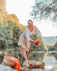 A village young peasant woman in folk slavic clothes washes clothes on a summer day on the river