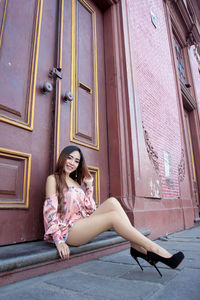 Full length of woman sitting outside building