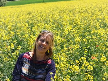 Portrait of smiling woman with yellow flowers in field