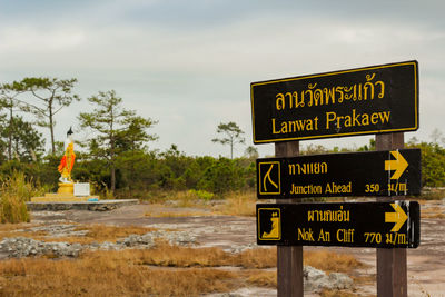 Information sign by trees against sky