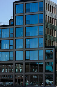 Low angle view of glass building against blue sky