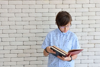 Boy holding book against wall