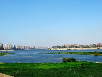 Scenic view of river by buildings against clear sky