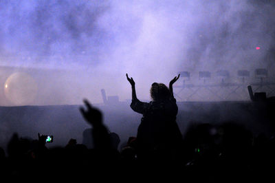 Silhouette people at music concert against sky at night