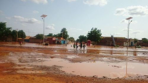 Reflection of people in puddle against sky