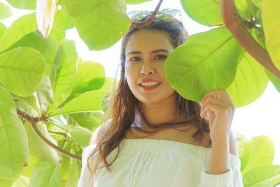 Portrait of smiling woman standing by plants