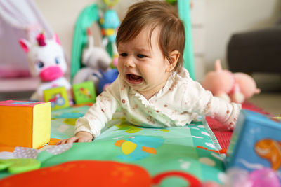 Baby girl crying while lying down at home