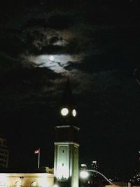 Illuminated street light in city against sky at night