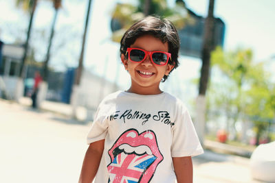 Portrait of smiling boy wearing sunglasses standing outdoors