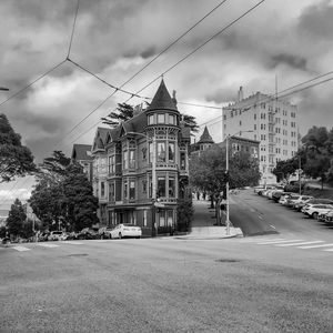 Road by buildings in city against sky