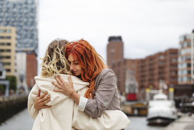 Smiling mother hugging daughter at elbphilharmonie in hafencity