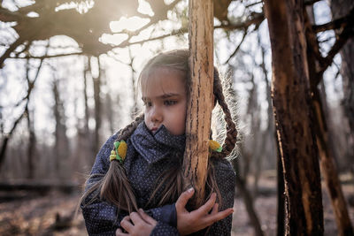 Portrait of girl holding tree trunk
