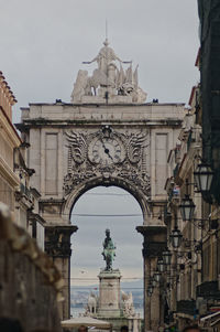 Statue in city against sky