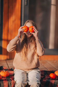 Girl holding pumpkin against face