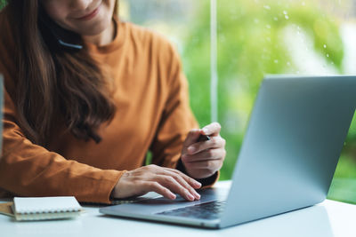 Midsection of woman using laptop at table