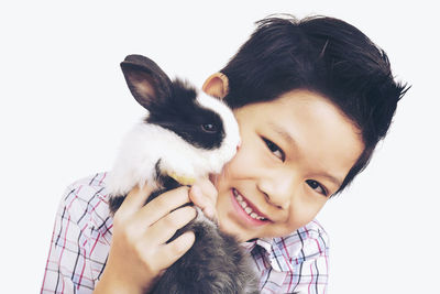 Portrait of smiling boy with rabbit against white background