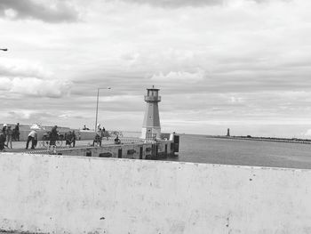 Lighthouse by sea against sky