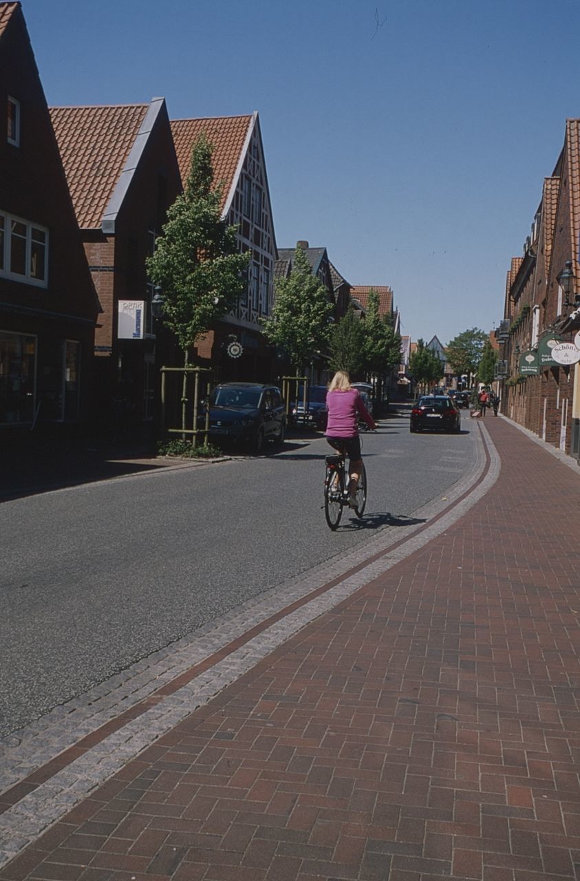 building exterior, architecture, built structure, transportation, bicycle, city, sky, mode of transportation, building, land vehicle, one person, street, real people, riding, clear sky, day, ride, nature, residential district, outdoors