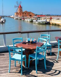 Chairs and tables by sea against clear sky