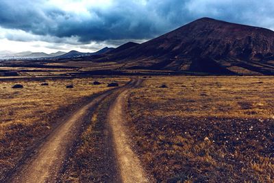 Dirt road along landscape and against clouds