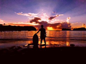 Silhouette men standing on beach against sky during sunset