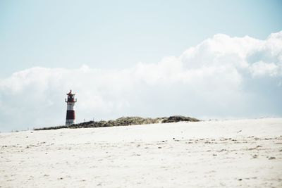 Lighthouse by sea against sky