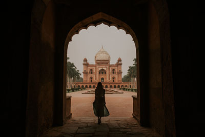Full body back view silhouette of anonymous female tourist admiring historic building of safdarjungs tomb in new delhi