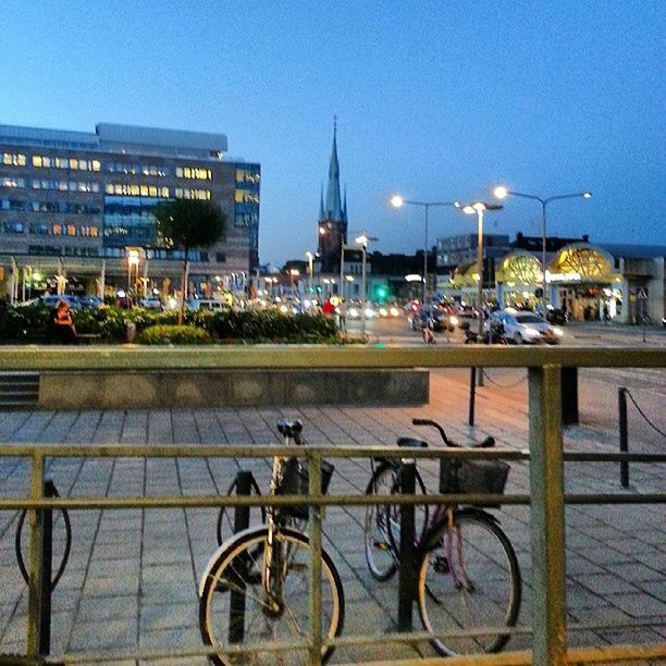 transportation, mode of transport, building exterior, city, architecture, built structure, land vehicle, street, clear sky, street light, car, city life, illuminated, travel, incidental people, parking, stationary, blue, bicycle, sky