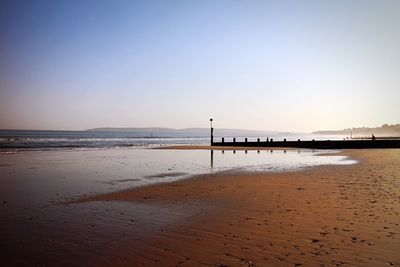 Scenic view of beach against clear sky during sunset