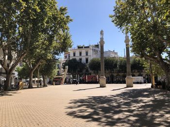 Street amidst trees and buildings against sky