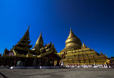 Temple against building against clear blue sky