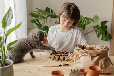 A girl with a kitten plants seeds in peat pots. funny pets. transplanting and growing plants at hom