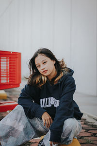 Portrait of woman sitting against wall