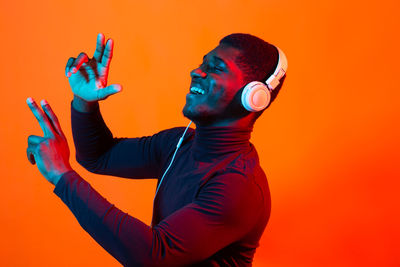 Side view of young man against orange background