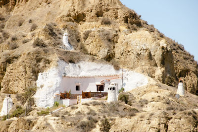 House on rock formation amidst buildings against sky