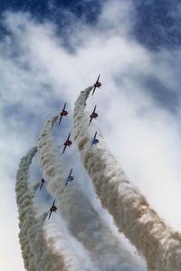 Low angle view of airplanes with trails in flight