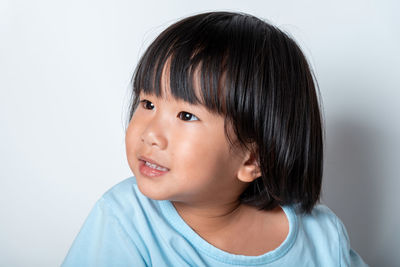 Portrait of cute girl looking away against white background