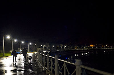 People on footbridge over river at night