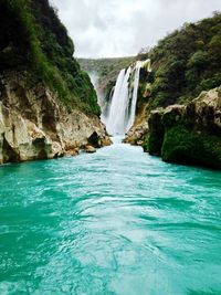 Scenic view of waterfall against sky